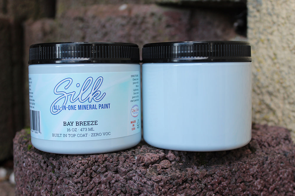 Peinture Silk de Dixie Belle. Couleur "Bay Breeze". Ce blanc élégant et nautique a une douce nuance de bleu et de gris pour apporter une touche de ciel à votre décor blanc ! La peinture Silk All-In-One est une peinture crémeuse et auto nivelante en une seule étape. Il a un bloqueur de taches intégré (à base d'eau), un apprêt et une couche de finition. Résistante à la moisissure. Vous pouvez utiliser cette peinture à l'intérieur car elle est inodore et non toxique.