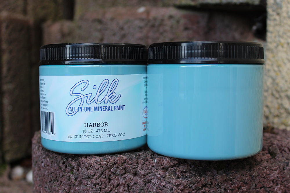 Peinture Silk de Dixie Belle. Couleur "Harbor" un bleu céruléen qui a de légères nuances de gris. La peinture Silk All-In-One est une peinture crémeuse et auto nivelante en une seule étape. Il a un bloqueur de taches intégré (à base d'eau), un apprêt et une couche de finition. La peinture a une finition peu réfléchissante et est résistante à la moisissure. Vous pouvez utiliser cette peinture à l'intérieur car elle est inodore et non toxique.